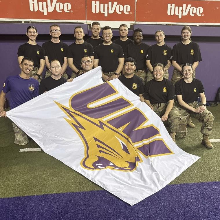 UNI ROTC cadets at football game with large panthers flag