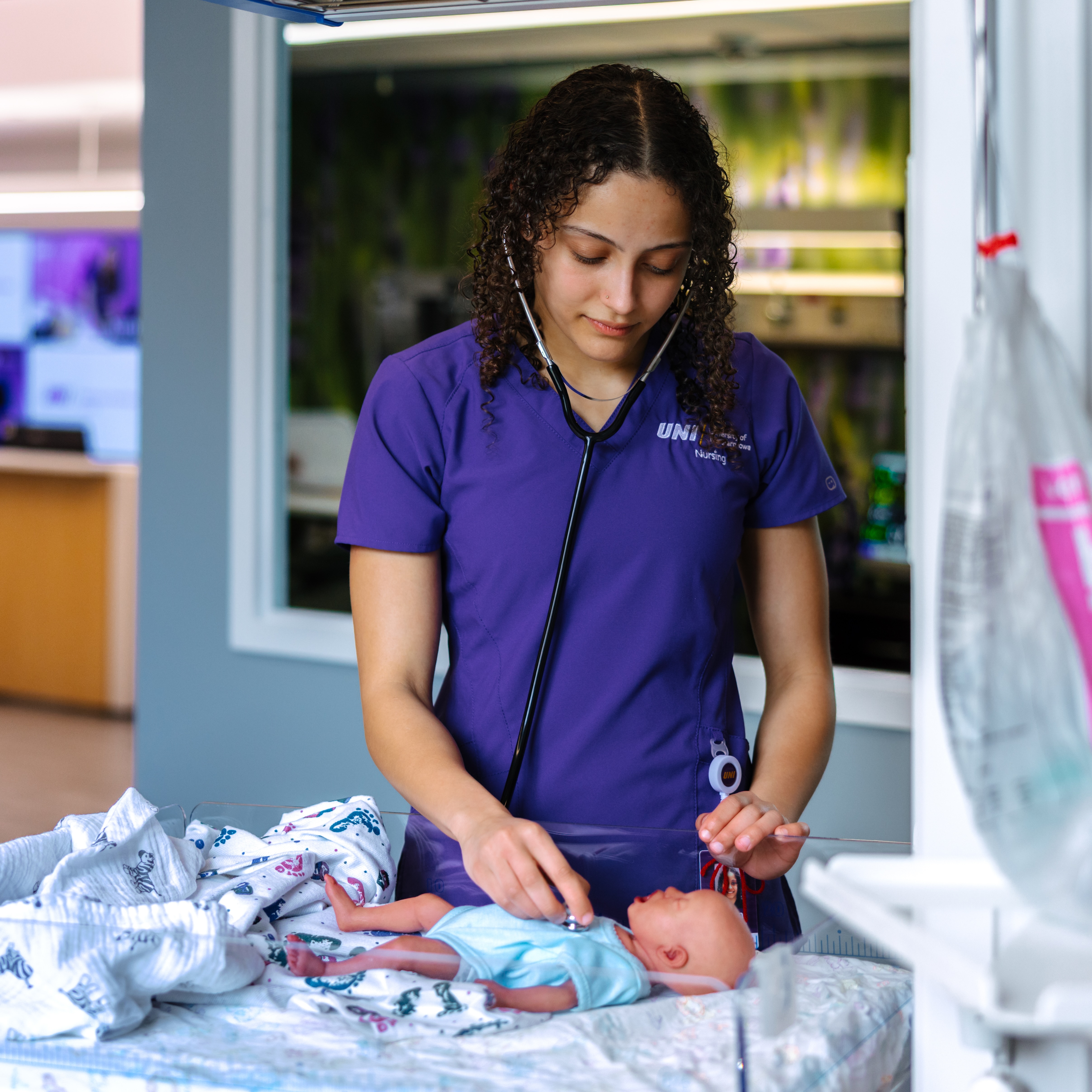 Nursing student in maternity simulation suite with infant manikin
