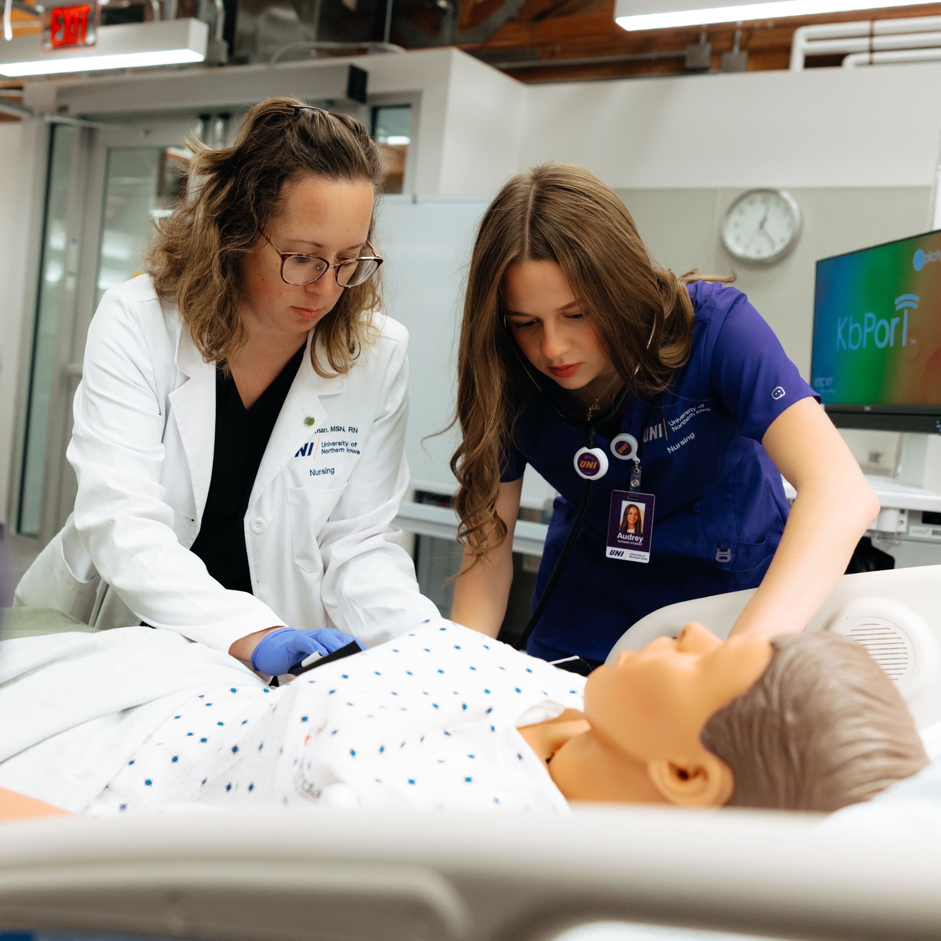 Nursing faculty and student working on manikin in integrated classroom
