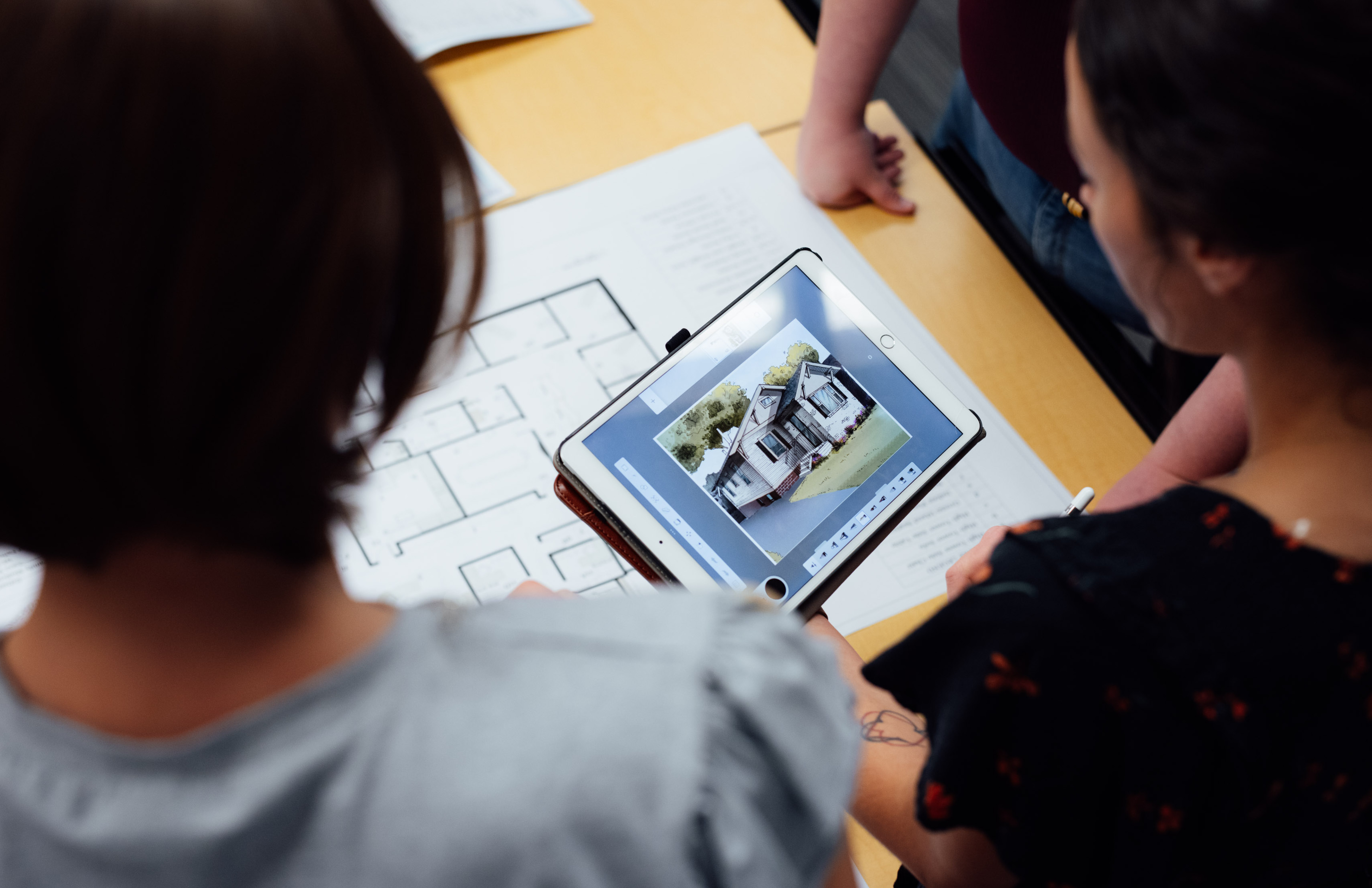 interior design students overlooking house on ipad with designs