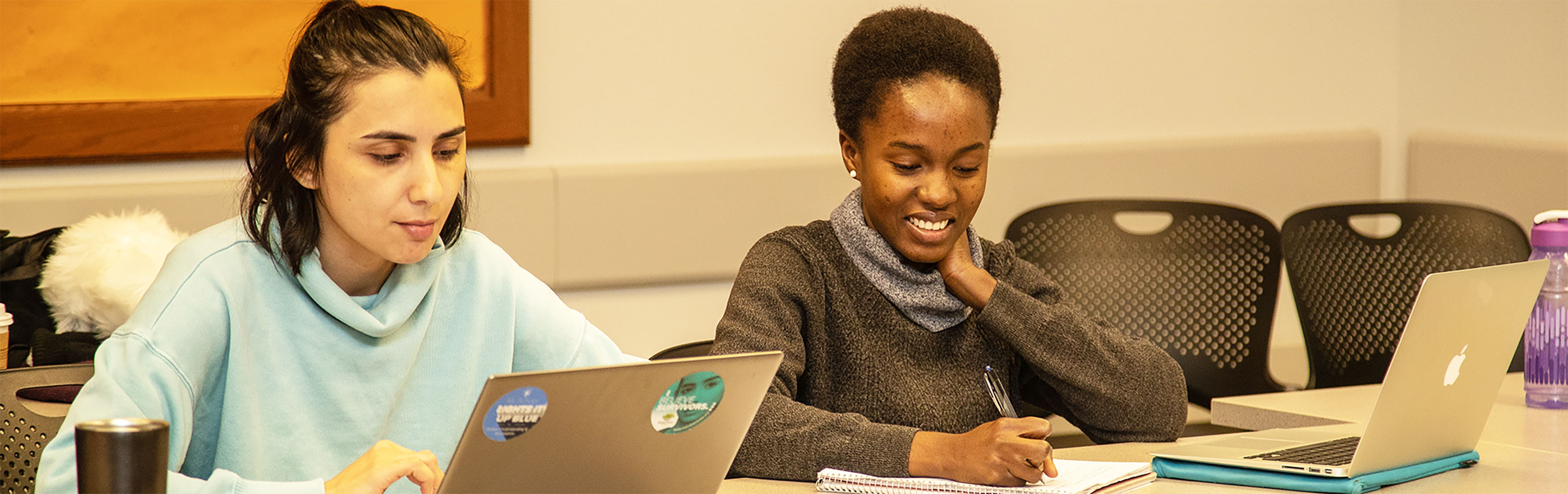 Two students studying with laptops in front of them.