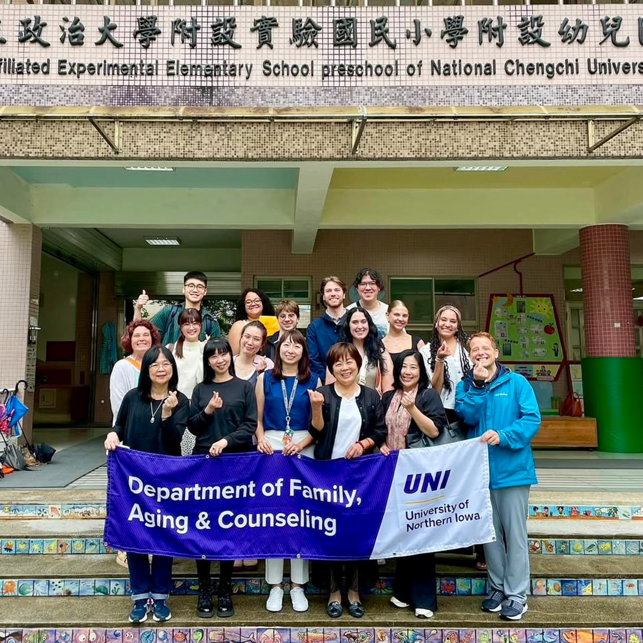 UNI Counseling Program students and faculty holding a UNI banner and posing with colleagues in Taiwan 