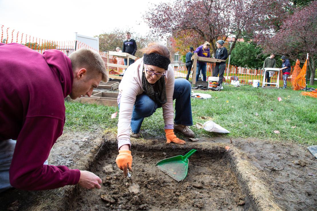 Students and faculty performing archeological dig on campus