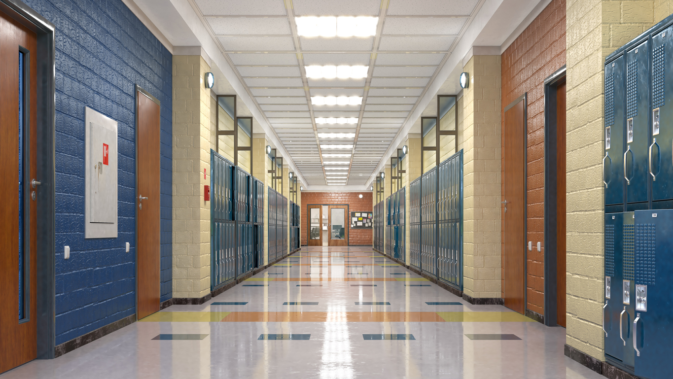 View down a school hallway, lined with lockers and classroom doors.