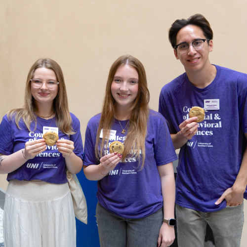 Three students smiling while holding cookies